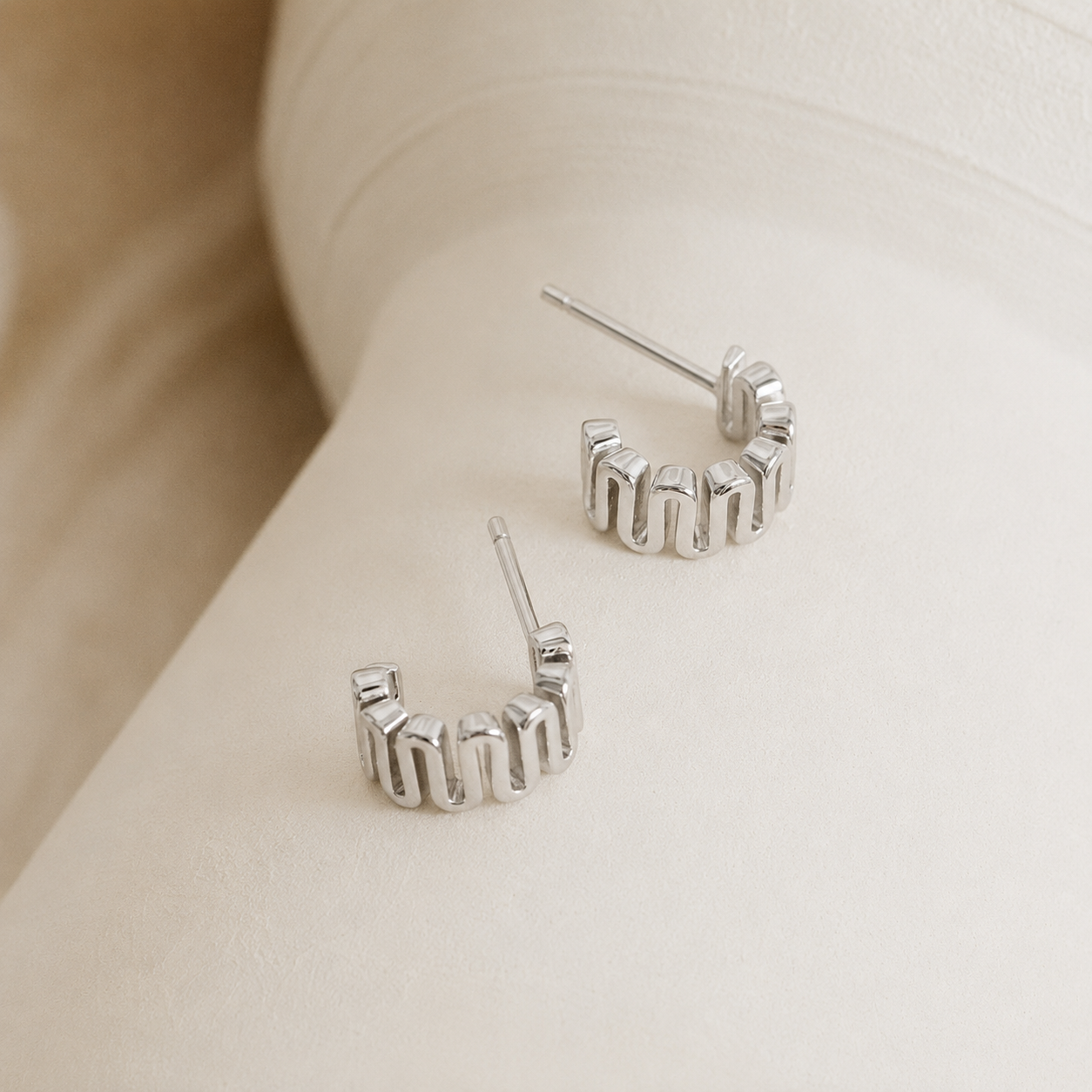 Silver hoop earrings on a neutral background